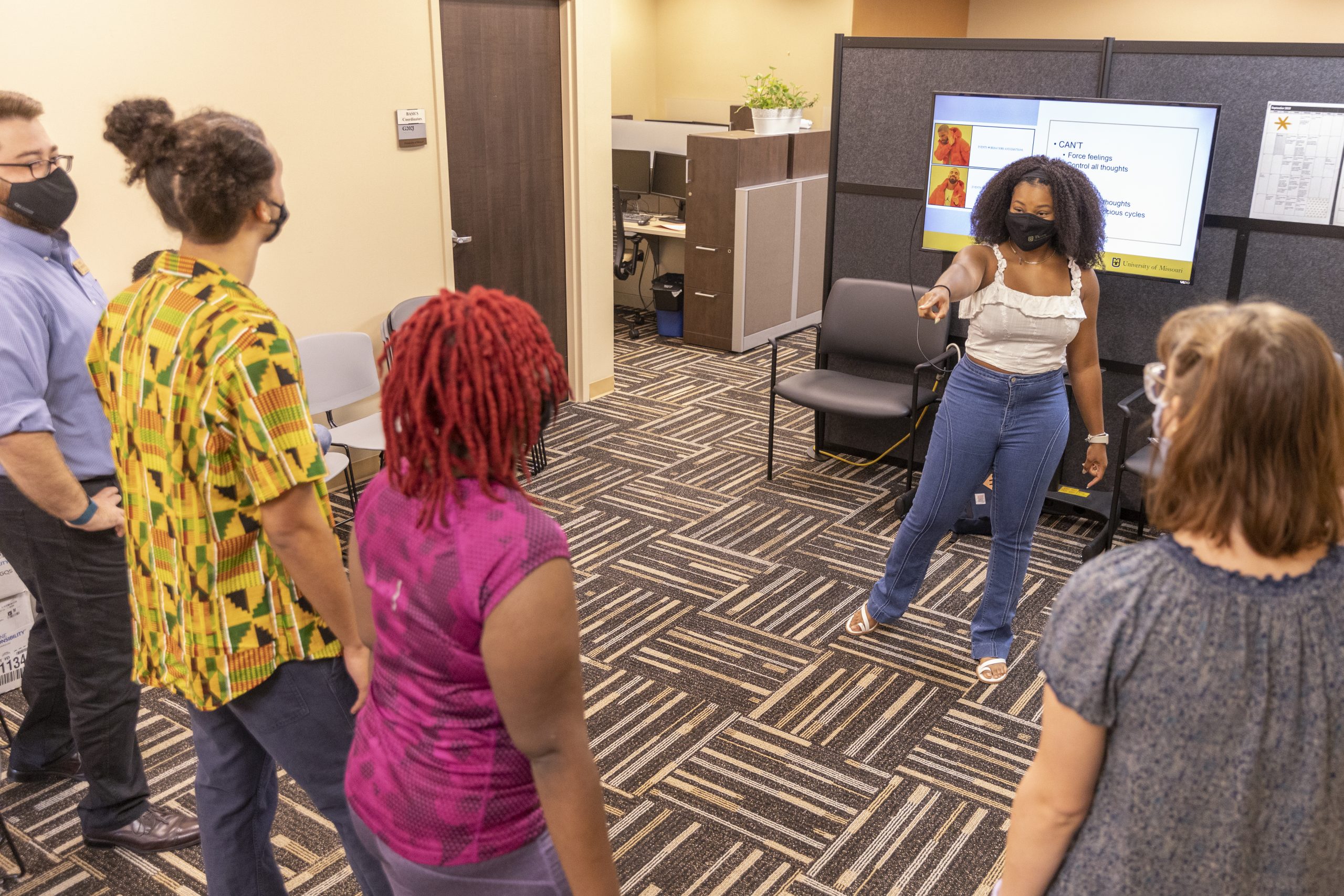 A woman in a mask leads a well-being workshop